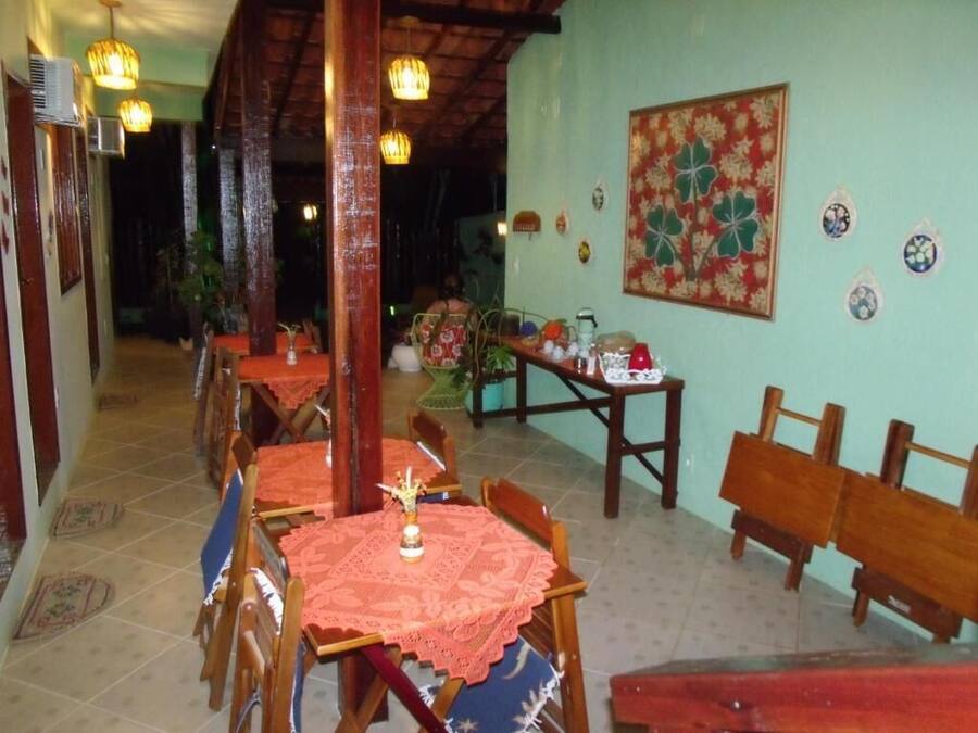 A dining area with wooden tables and chairs, a patterned wall, and hanging lights.