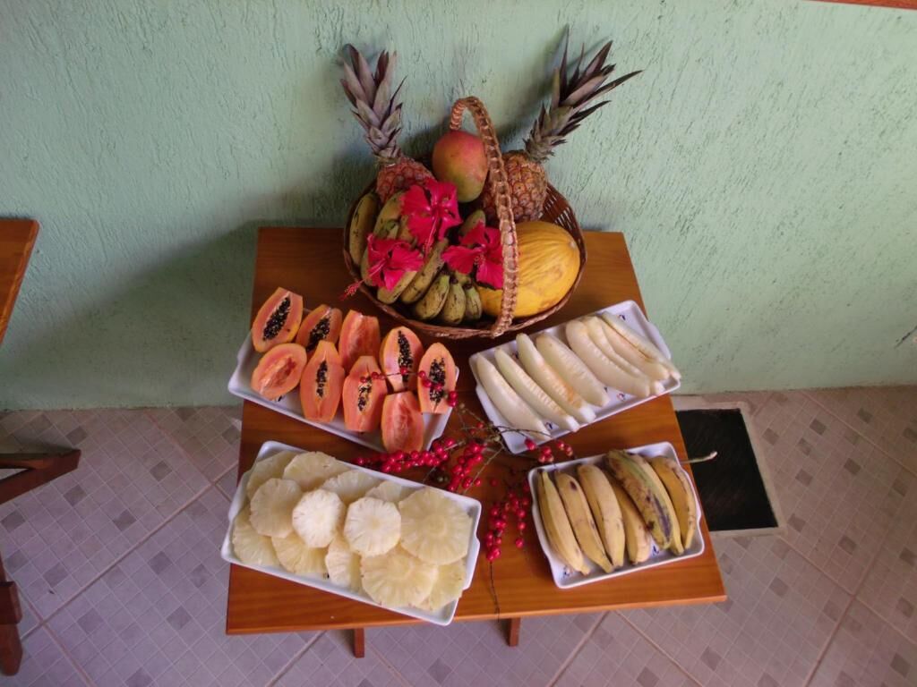 Una mesa de madera con tres bandejas de fruta cortada y una cesta de fruta entera.