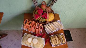 Una mesa de madera con tres bandejas de fruta cortada y una cesta de fruta entera.