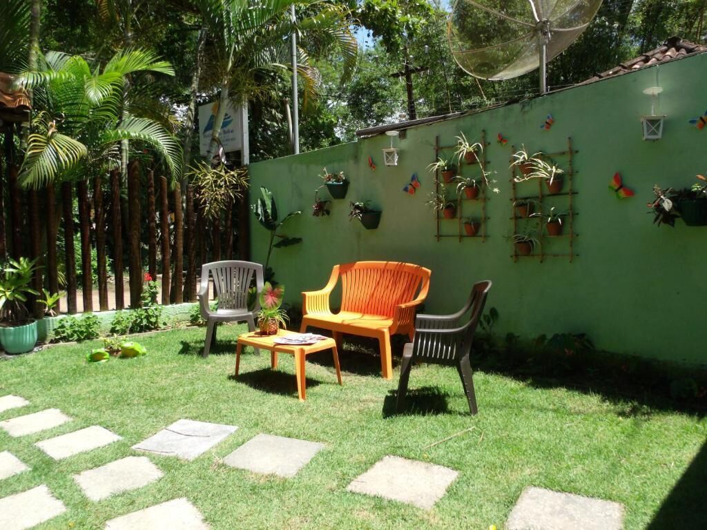 Un pati amb una paret verda, plantes en testos i mobiliari exterior.
