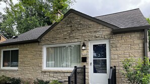 A stone house with a front door, a window, and a mailbox.