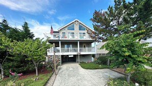 A two-story building with a balcony, a flag, and a sign that reads "Coconut Lagoon." - Oceanside home in Corolla with 4 bedrooms, 3 baths and private pool. (Corolla)