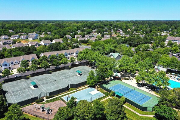 An aerial view of a residential area with multiple houses, a tennis court, and a swimming pool. - Great 3 BD ground floor condo in Bear Trap Dunes! Sleeps 6, Shuttle to the beach, Community Pool, great Amenities! NOW AVAILABLE FOR LONG TERM Discounts for 3 night, 5 night, and 7 night stays for August and September! (Ocean View)