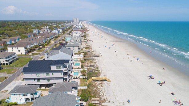 An aerial view of a coastal residential area with houses, a beach, and a clear sky. - Walk to the Beach 5 BR Beach House with a Private Pool! I Choose You  (Surfside Beach)
