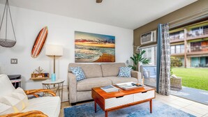 Una sala de estar con sofá, mesa de centro y un cuadro de una playa.