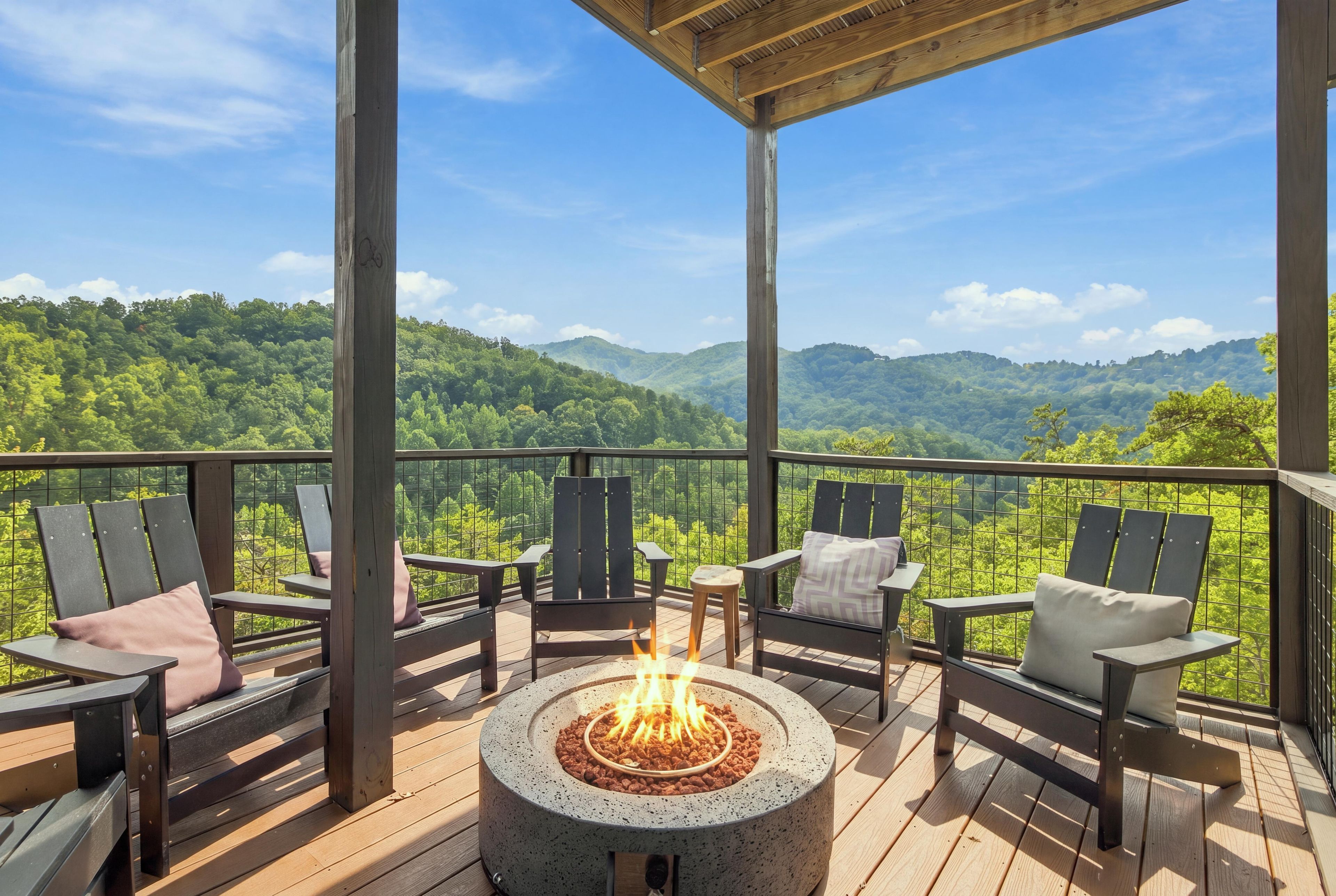 Une terrasse couverte avec des sièges d’extérieur et un foyer, offrant une vue sur un paysage boisé.