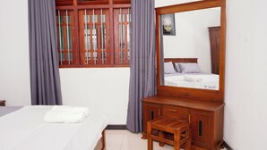 Une chambre à coucher avec un lit, une commode en bois, un miroir et une fenêtre avec des rideaux.