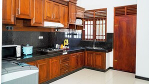 Une cuisine avec des meubles de rangement en bois, un four à micro-ondes, une cuisinière et un évier.