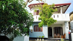 Une maison à deux étages dotée d’un balcon, d’un hall d’entrée carrelé et d’un petit jardin.