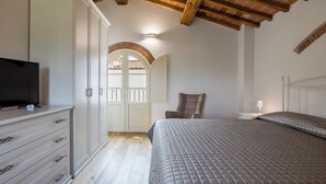 Un dormitorio con cama, televisión, armario y una silla.