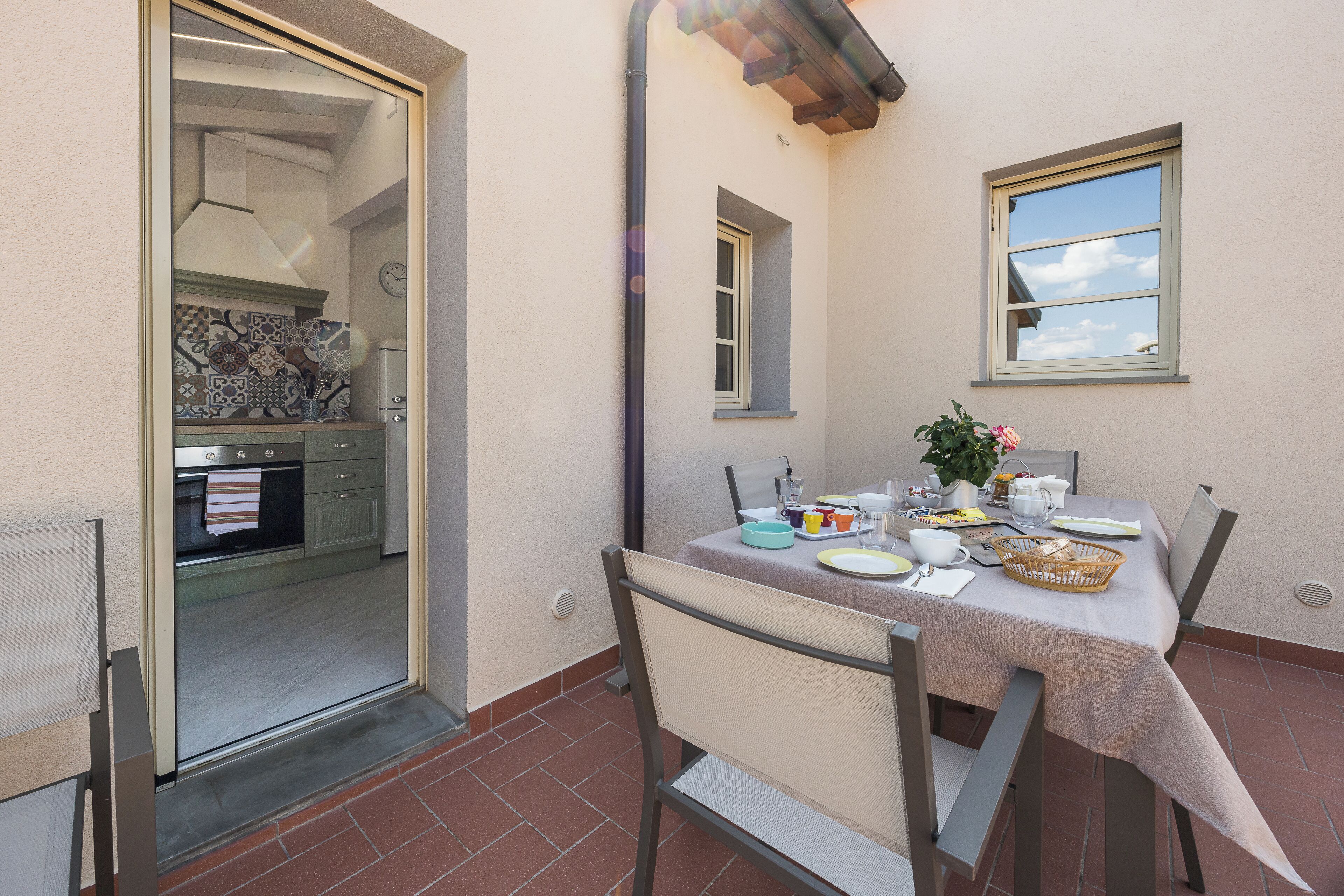 A dining area with a table set for two, a window, and a view of the kitchen.