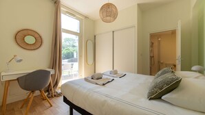 Een slaapkamer met een bed, een bureau, een stoel en een raam.