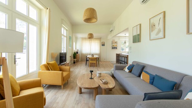 Een ruime zithoek met een bank, fauteuils en een salontafel. Achterin staat een eettafel met stoelen.
