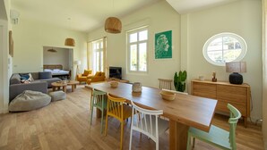 Een moderne woonkamer met een houten eettafel, kleurrijke stoelen, een bank en een televisie.