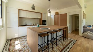 Een moderne keuken met een centraal eiland, barkrukken, hanglampen en een vloer met een patroon.