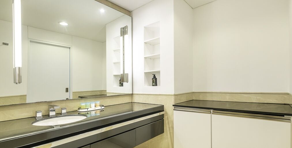 A modern bathroom with a large mirror, a sink, and a toilet.