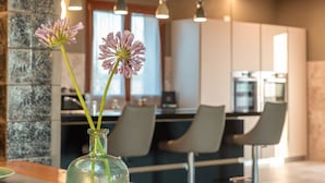 Een moderne keuken met een bakstenen plafond, hanglampen en een vaas met bloemen op een tafel.