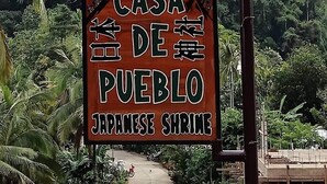A sign for 'Casa De Pueblo Japanese Shrimp' with a pathway leading to a building.