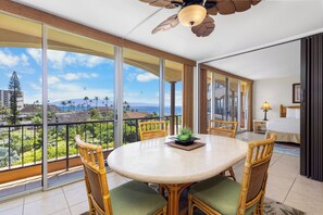 A balcony with a round table, chairs, and a potted plant.