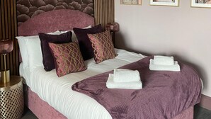 A bedroom with a large bed, a decorative headboard, and three framed artworks on the wall. - 
Cosy & Modern 1 Bed Apartment (Orpington)