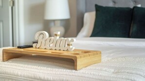 A bed with a wooden tray holding a sign that reads "Relax" and a remote control on it. - Feels Like Home! Columbia near Fort Jackson - Perfect for Families - Sleeps 6 (Elgin)