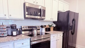 A modern kitchen with stainless steel appliances, white cabinetry, and a granite countertop. - Feels Like Home! Columbia near Fort Jackson - Perfect for Families - Sleeps 6 (Elgin)
