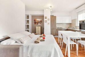 Una habitación de hotel moderna con una cama bien hecha, un comedor y una cocina.
