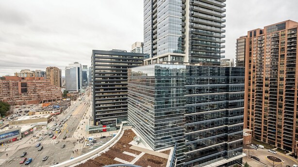A modern high-rise building with a glass facade, surrounded by other urban structures.