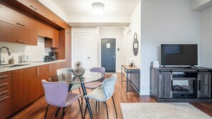 A modern kitchen with wooden cabinets, a glass dining table, and purple chairs.