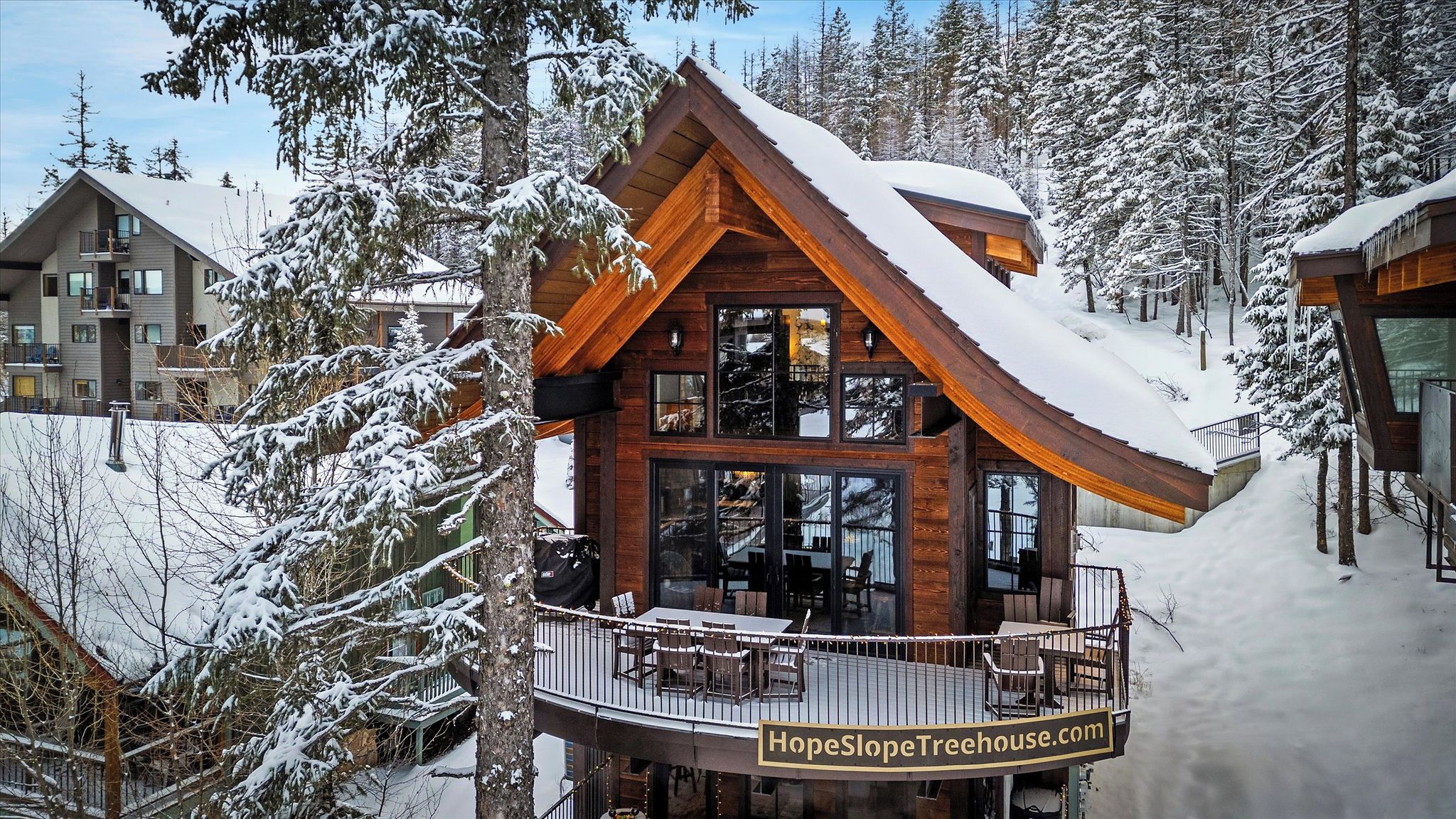A wooden cabin with a balcony, surrounded by snow-covered trees.