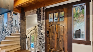 Una puerta de madera con un ventanal, una escalera y una pared con un diseño de rama de árbol.