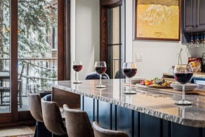 A bar area with a long counter, multiple wine glasses, and a selection of snacks.