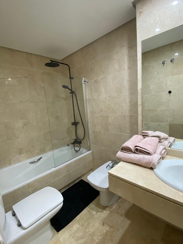 A modern bathroom with a bathtub, toilet, and sink.