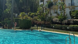Una piscina rodeada de palmeras y un edificio con balcones.