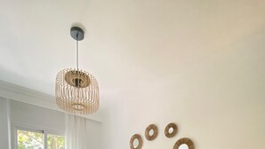 Un dormitorio con cama, lámpara de noche, ventana con cortinas y adornos en la pared.