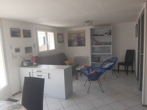 A modern, well-lit room with a white desk, two blue chairs, a bookshelf, and a window. - Maison Guilvinec à 1 min à Pied de la Plage (Guilvinec)