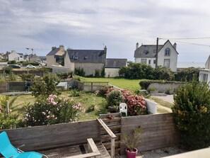 A residential backyard with a wooden bench, a potted plant, and a variety of flowering plants. - Maison Guilvinec à 1 min à Pied de la Plage (Guilvinec)