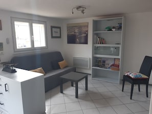 A modern living room with a grey sofa, a small table, a bookshelf, and a chair. - Maison Guilvinec à 1 min à Pied de la Plage (Guilvinec)
