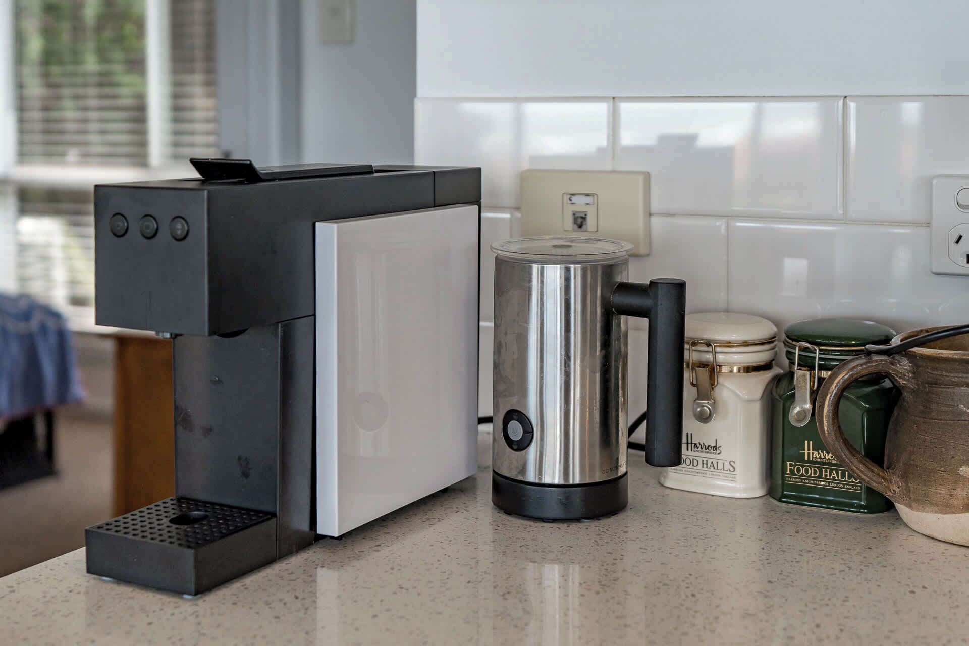 Eine Küche mit einer Kaffeemaschine, einem Wasserkocher und einem Glas auf der Arbeitsplatte.