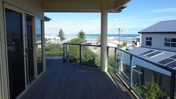 A balcony with a view of the ocean and a neighboring house.