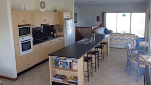 A modern kitchen with a central island, built-in appliances, and a dining area with bar stools.
