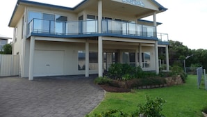 A two-story building with a balcony, a garage, and a landscaped garden.