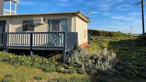 Une maison de plain-pied avec un balcon, un petit garage attenant et un jardin où poussent des fleurs jaunes.