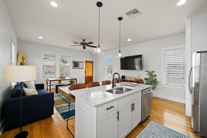 A modern kitchen with a central island, white cabinetry, and stainless steel appliances.