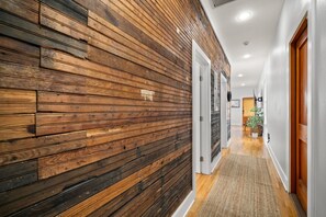 Ein Korridor mit Holzwandverkleidung, einer weißen Tür und einer Pflanze im Hintergrund.