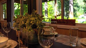 Una mesa de comedor dispuesta con platos, vasos y una planta en maceta.