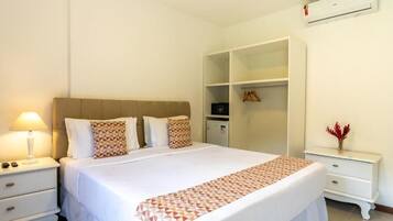 Un dormitorio ordenado con cama, mesitas de noche, un armario y un aire acondicionado.