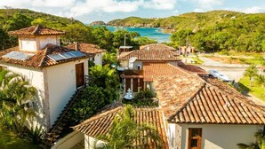 Un pueblo costero con edificios de tejas color terracota, abundante vegetación y vista al mar.