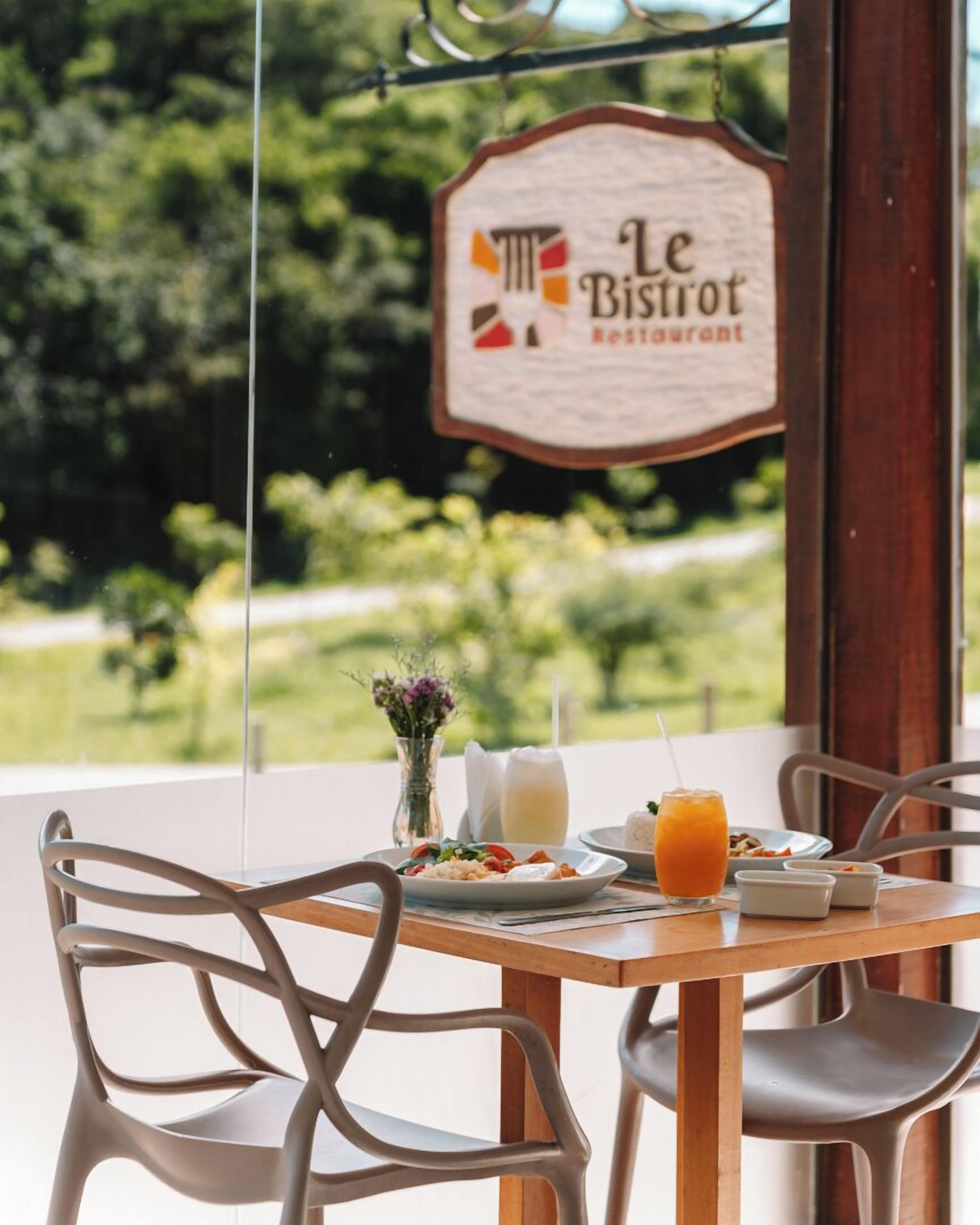 A table with a sign reading "Le Bistro Restaurant" and a view of greenery outside.