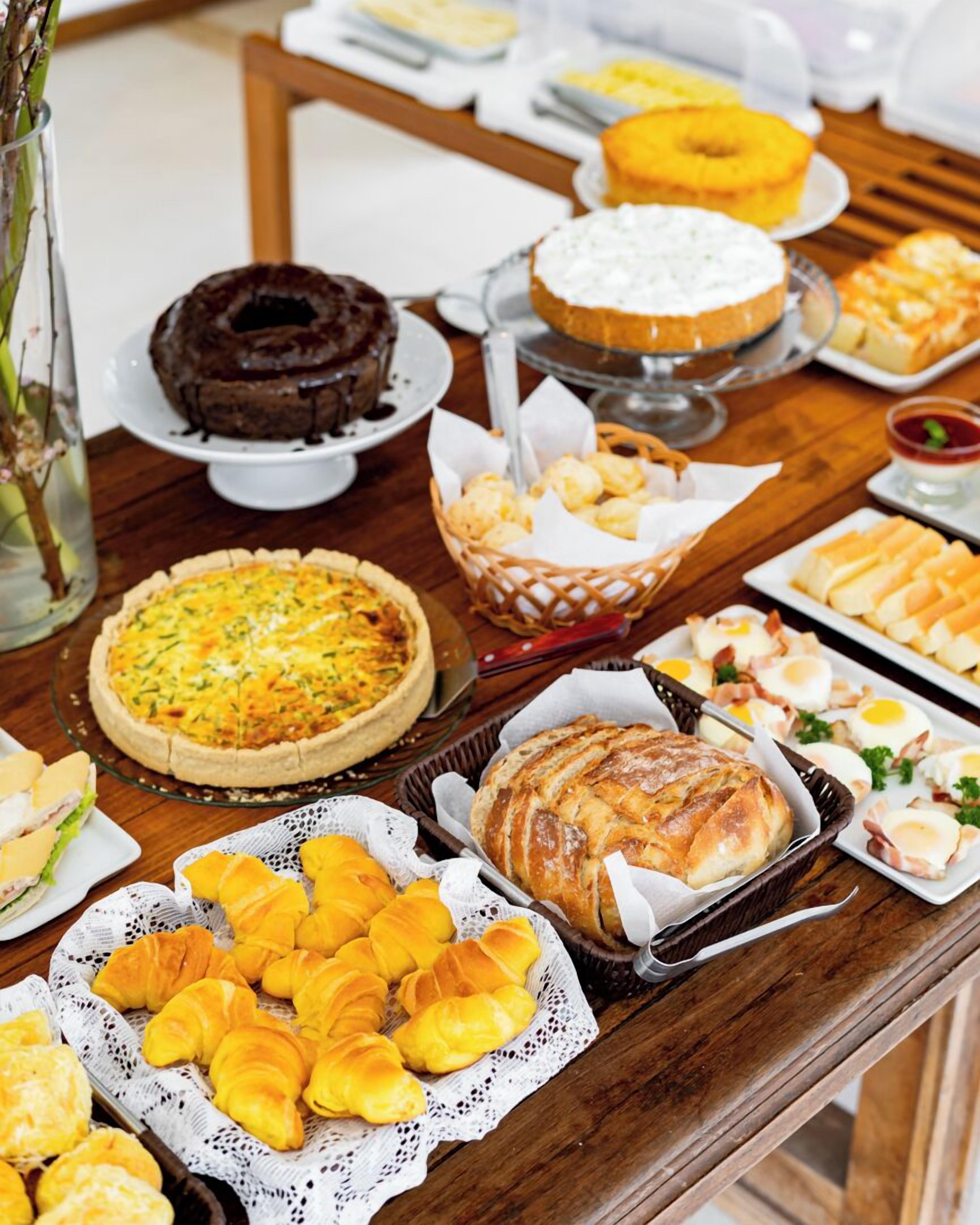 A buffet table with various food items including a quiche, croissants, and a chocolate cake.
